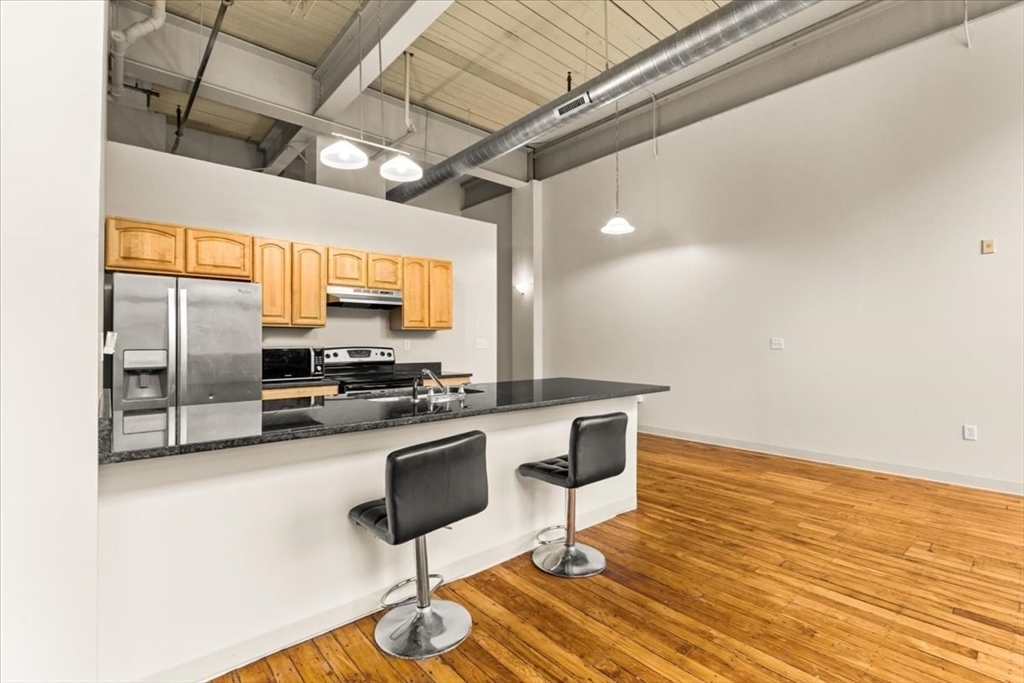 685 Social Street, Unit 215 Woonsocket, RI 02895 - Photo 34 of 40 a kitchen with stainless steel appliances kitchen island granite countertop a stove and cabinets