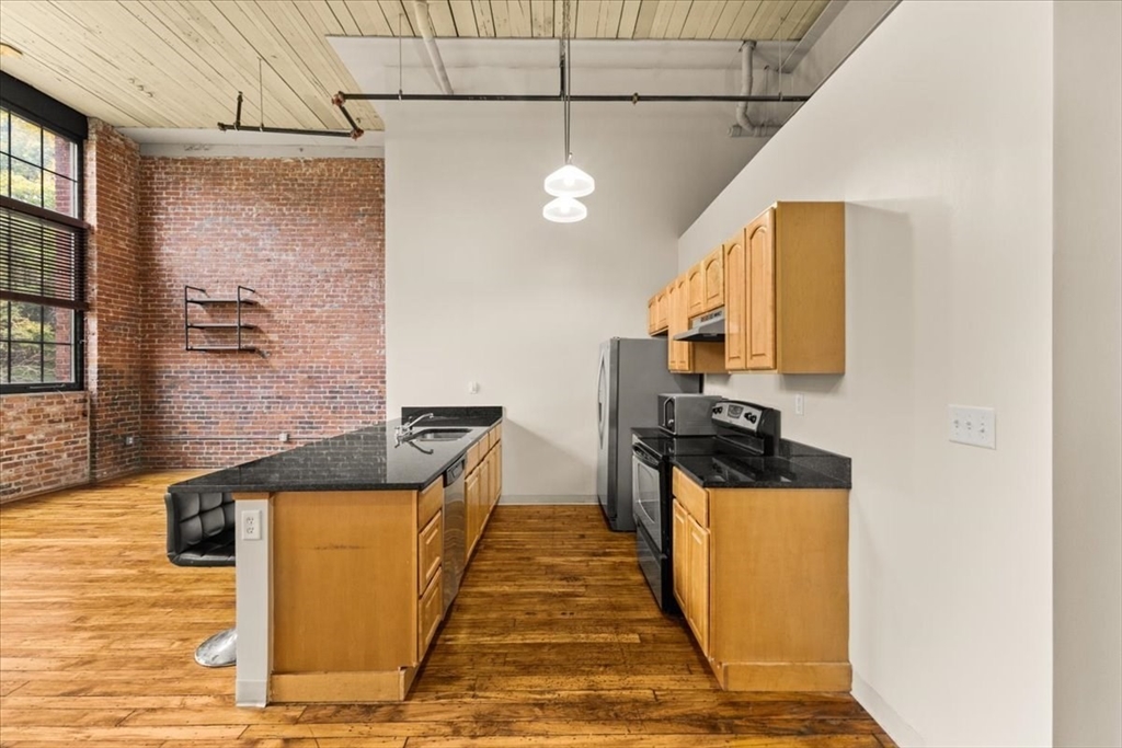 685 Social Street, Unit 215 Woonsocket, RI 02895 - Photo 37 of 40 a kitchen with stainless steel appliances granite countertop a stove a sink and a refrigerator