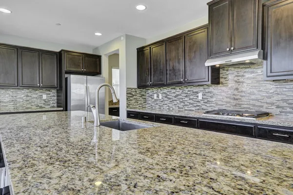 a kitchen with kitchen island granite countertop a stove a sink and a microwave