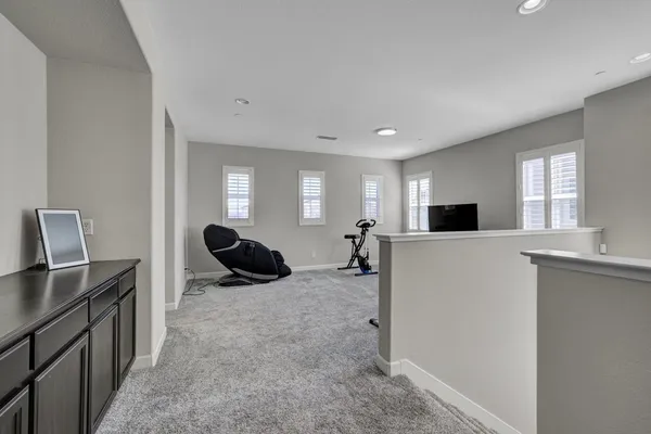 a living room with furniture a flat screen tv and a refrigerator