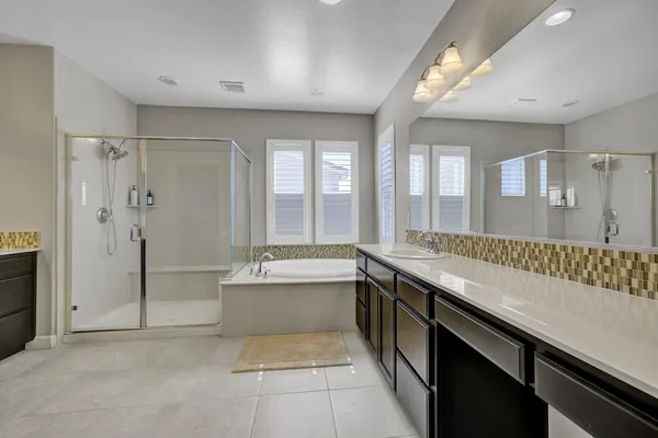a large bathroom with a double vanity sink a large mirror and a bathtub