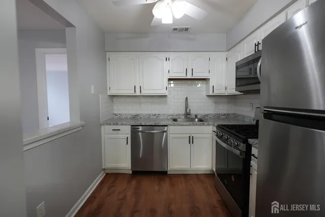 a kitchen with stainless steel appliances granite countertop a refrigerator stove a sink and dishwasher a refrigerator with white cabinets