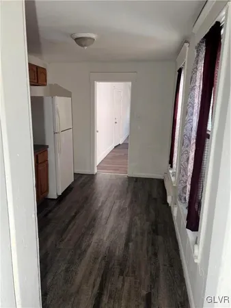 a view of a hallway with wooden floor and a bathroom