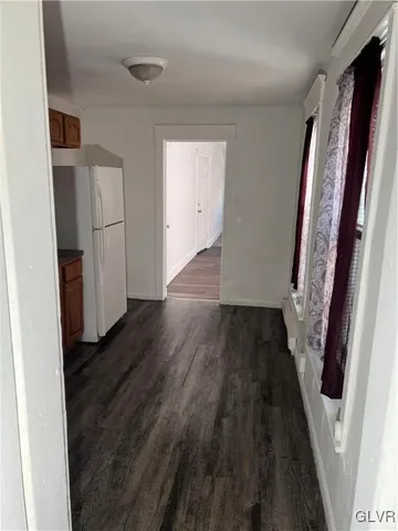 a view of a hallway with wooden floor and a bathroom