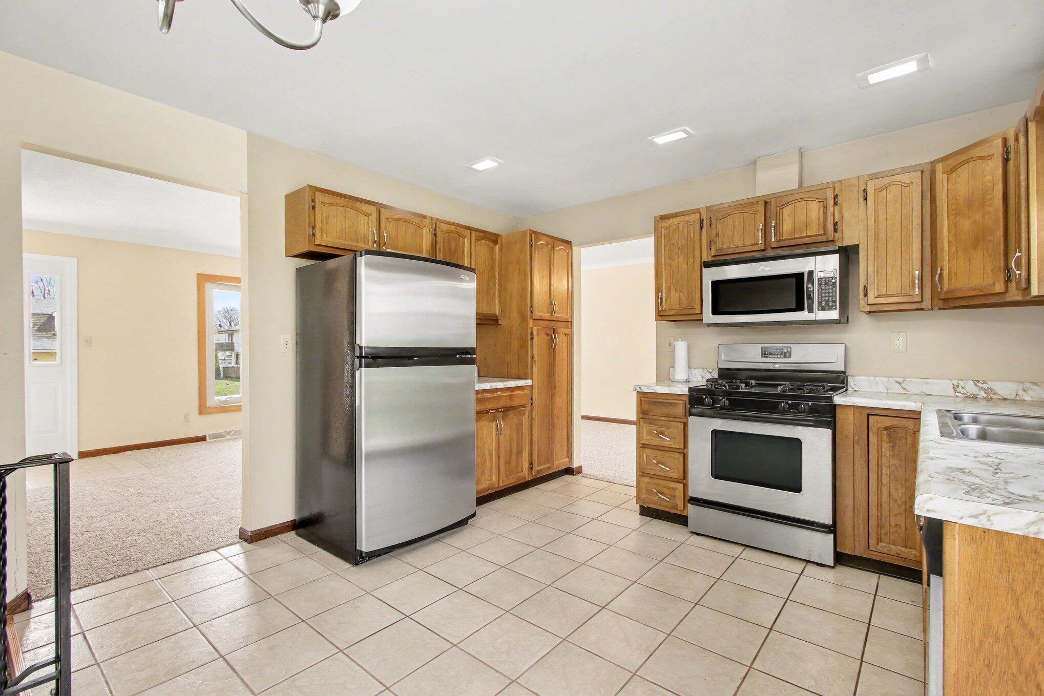 1379 Leeward Road Crown Point, IN 46307 - Photo 13 of 39 a kitchen with granite countertop a refrigerator and a stove top oven