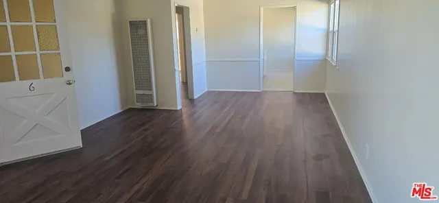 an empty room with wooden floor and a sink