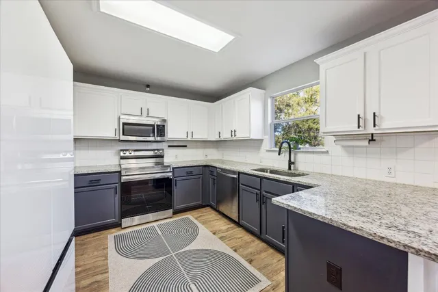 a kitchen with stainless steel appliances granite countertop a stove top oven a sink a dining table and chairs