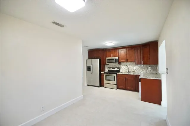 a large kitchen with stainless steel appliances granite countertop a refrigerator and a sink