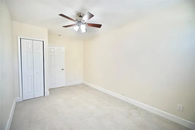 an empty room with a ceiling fan and a window