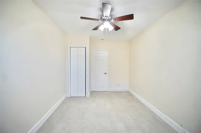 an empty room with a ceiling fan and a window