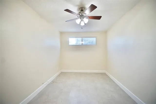 an empty room with a chandelier fan and windows