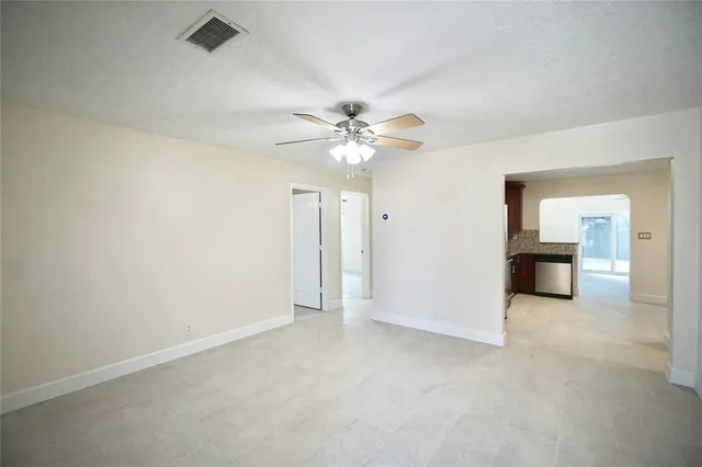 an empty room with a chandelier fan and windows
