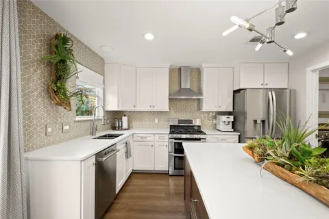 a kitchen with a sink a counter top space stainless steel appliances and cabinets