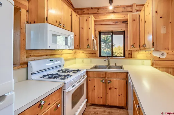 a very nice looking kitchen with granite countertop a stove two sinks and a chandelier