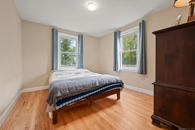 a bedroom with a bed window and a wooden floor