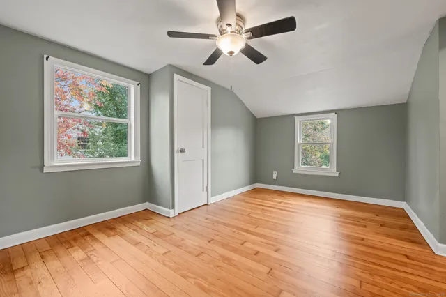 a view of empty room with wooden floor and fan