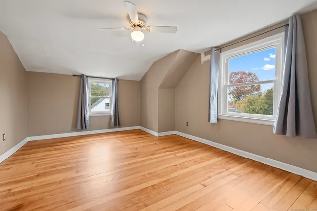 a view of empty room with wooden floor and fan