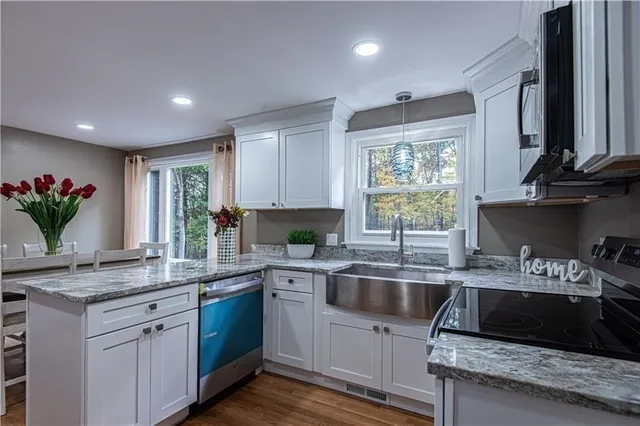 a kitchen with kitchen island granite countertop a sink a counter space appliances and cabinets