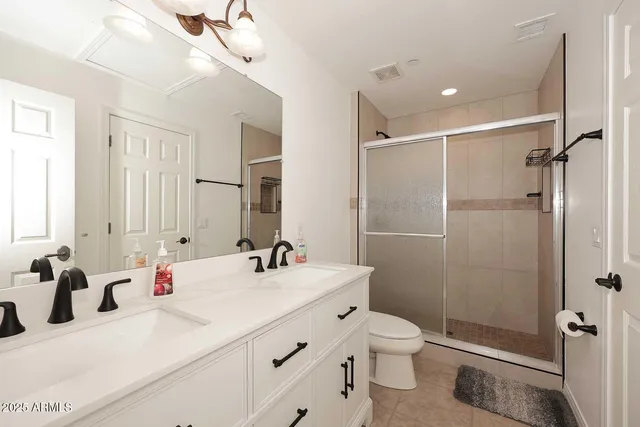 a bathroom with a sink toilet double vanity and shower