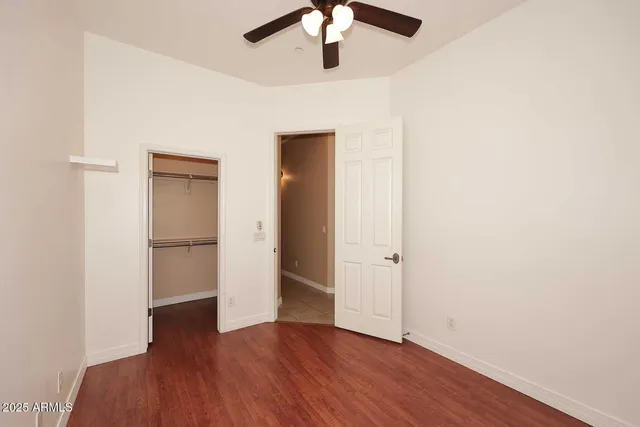 an empty room with wooden floor closet and windows