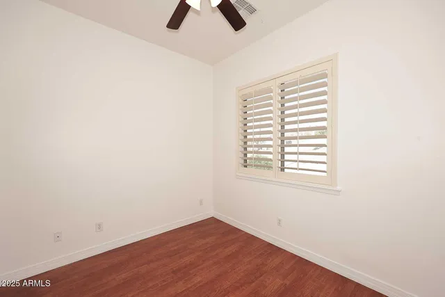 an empty room with ceiling fan and window