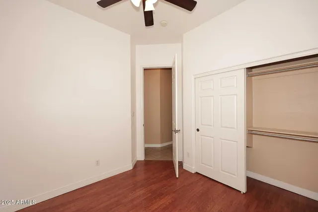 an empty room with wooden floor and ceiling fan