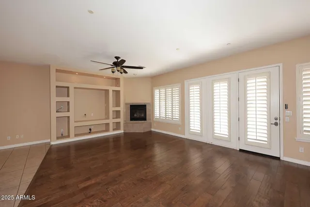 an empty room with wooden floor chandelier and windows