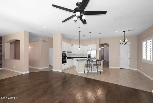 a dining room with wooden floor a chandelier fan a wooden table and chairs