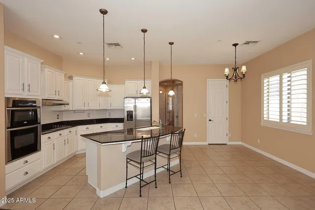 a kitchen with stainless steel appliances granite countertop a stove a sink and chairs