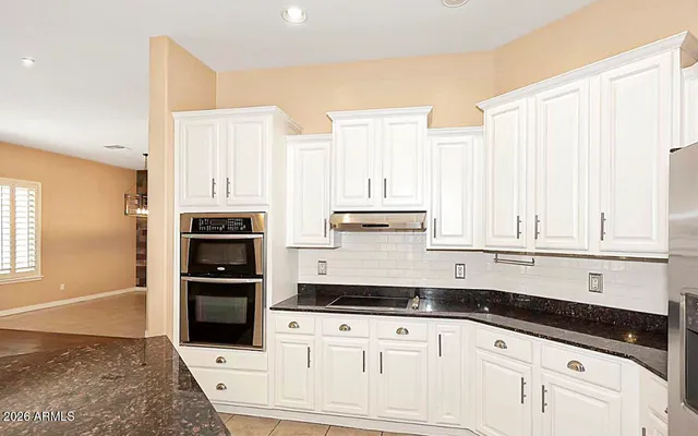 a kitchen with granite countertop white cabinets and stainless steel appliances