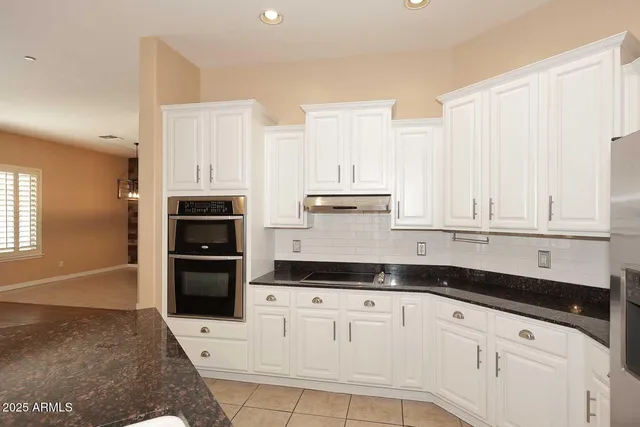 a kitchen with granite countertop white cabinets and refrigerator