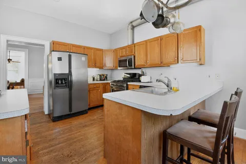 a kitchen with stainless steel appliances a refrigerator a sink a stove and chairs