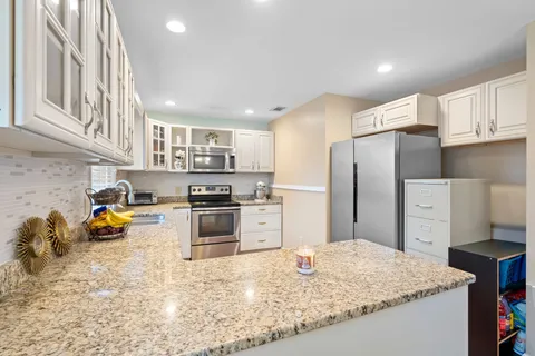 a kitchen with stainless steel appliances granite countertop a refrigerator a stove and a sink