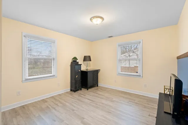 a view of an empty room with a window and wooden floor