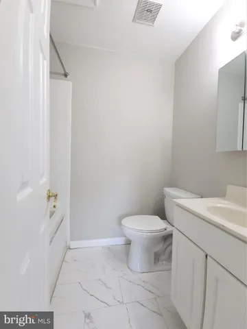 a white toilet sitting next to a bathroom sink and vanity