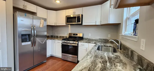 a kitchen with stainless steel appliances granite countertop a stove a refrigerator and a microwave