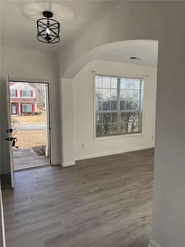 an empty room with wooden floor closet and windows
