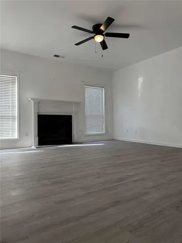 an empty room with wooden floor a ceiling fan and a fireplace
