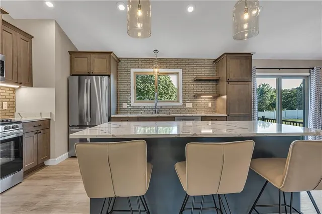 a kitchen with stainless steel appliances granite countertop a stove a refrigerator a sink dishwasher a dining table and chairs with wooden floor