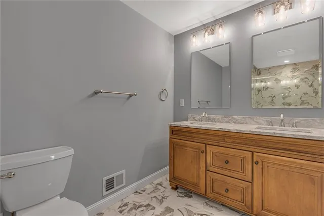 a bathroom with a granite countertop toilet sink and mirror