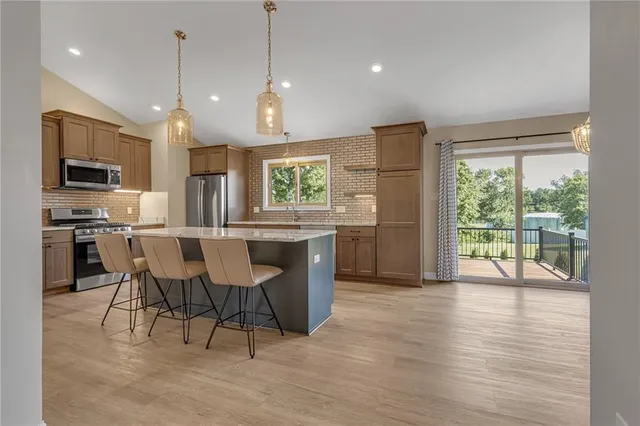 a open kitchen with stainless steel appliances granite countertop a stove a refrigerator a oven a sink with a dining table and chairs