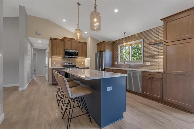 a kitchen with stainless steel appliances granite countertop a stove a sink a refrigerator and a microwave