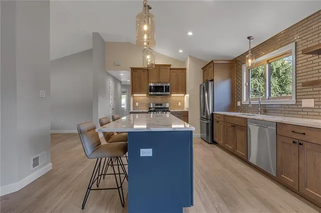 a kitchen with kitchen island granite countertop wooden floors and stainless steel appliances