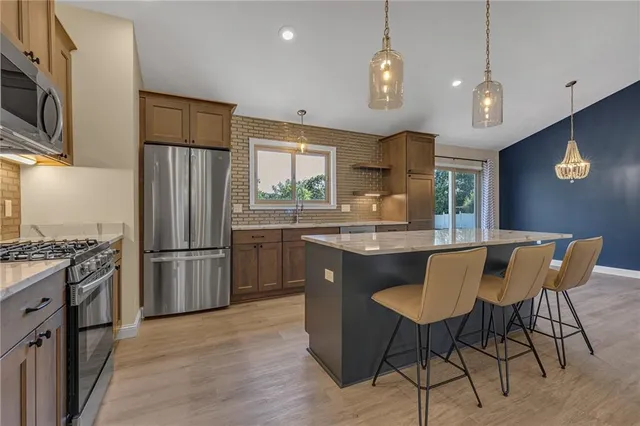 a kitchen with stainless steel appliances granite countertop a refrigerator a stove a sink dishwasher a dining table and chairs with wooden floor