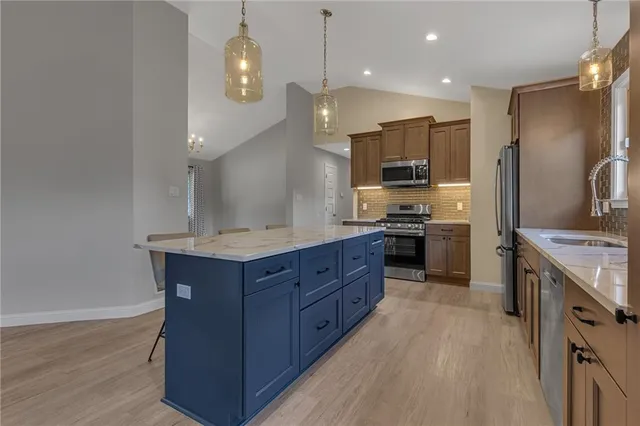 a kitchen with stainless steel appliances granite countertop a stove a sink and a refrigerator