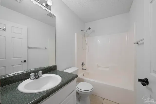 a bathroom with a granite countertop bathtub shower sink vanity and toilet