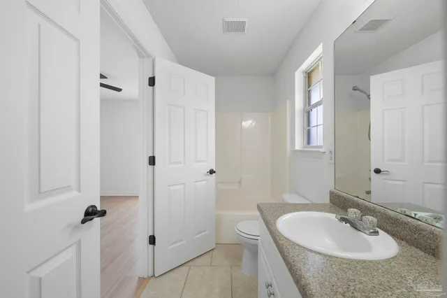 a bathroom with a granite countertop sink toilet and large mirror