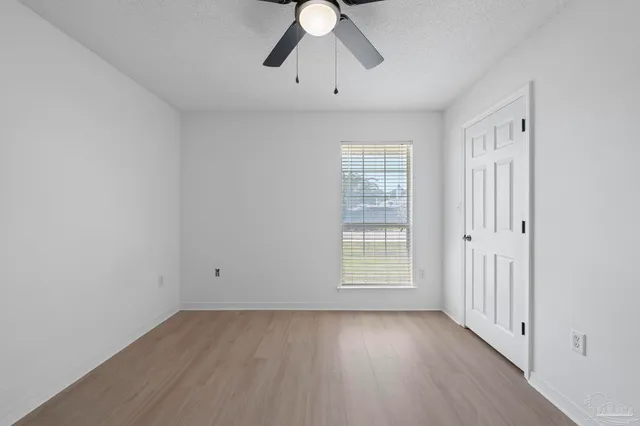 a view of empty room with wooden floor and window