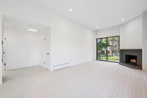 a view of an empty room with a window and fireplace