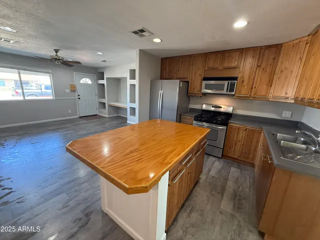 a kitchen with stainless steel appliances a sink a stove top oven a refrigerator cabinets and wooden floor